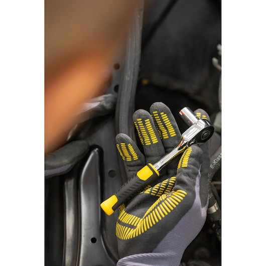 STANLEY STMT82663-0 ratchet wrench with yellow and black handle held in a gloved hand during use.