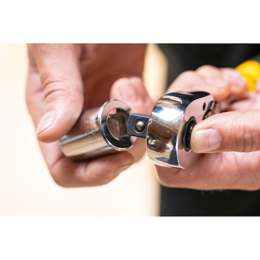 STANLEY STMT82664-0 ratchet handle with chrome socket attachment held by hand.