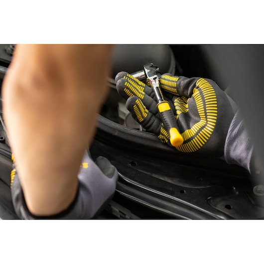 STANLEY STMT82672-0 ratchet held by gloved hand during automotive maintenance, black and yellow grip visible.
