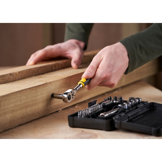 STANLEY STMT82672-0 ratchet set used on wood, close-up angle, open case with sockets and bits visible.