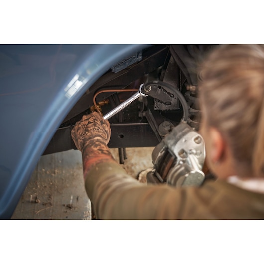 Photo of person using STANLEY STMT82843-0 combination wrench on car part, side view.