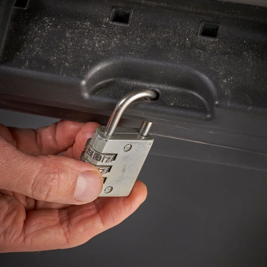 Photo of STANLEY STST1-70715 storage box with a hand placing a combination padlock in the front latch.