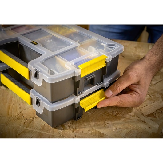 STANLEY STST1-70720 organizer box with yellow latch, stacked, close-up of hand opening latch.
