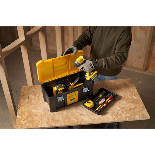 STANLEY STST75787-1 tool box with yellow lid, filled with power tools and accessories on a workbench.