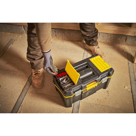 STANLEY STST83397-1 black and yellow toolbox with open compartments and assorted tools, top view in workshop.