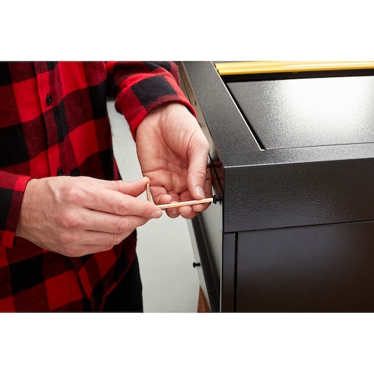 STANLEY STST97598-1 photography of person using hex key on black metal cabinet corner.
