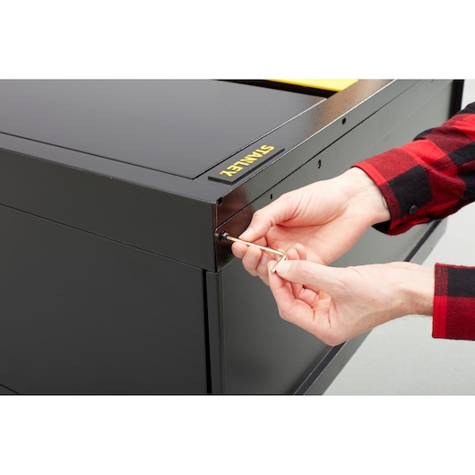 STANLEY STST97957-1 photography of black metal cabinet being assembled with hex key, angled view.