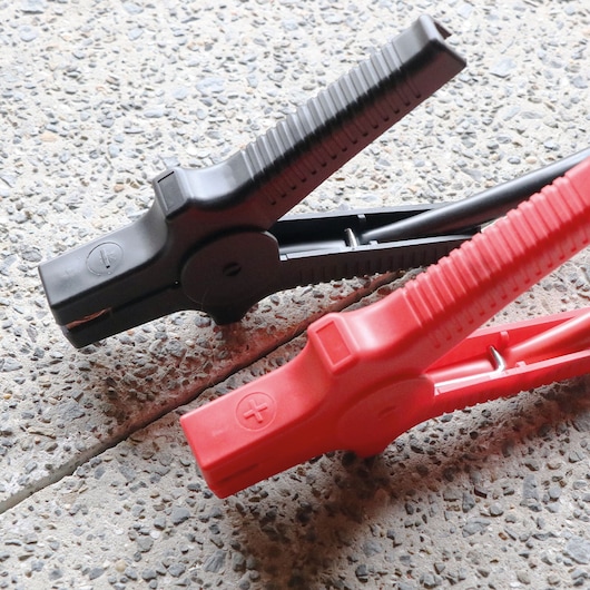 STANLEY SXAE00014 jumper cable clamps, red and black, close-up photography on concrete surface.