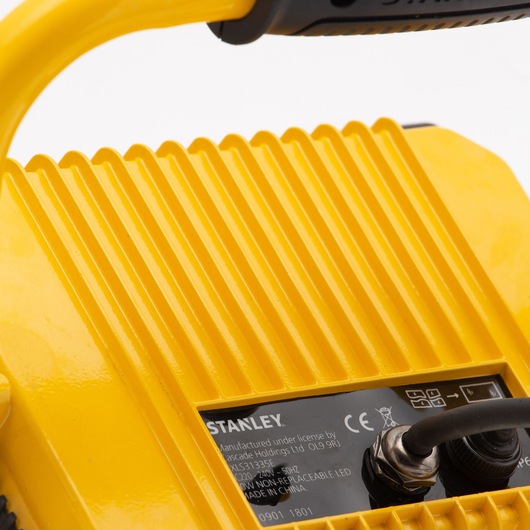 Photo of STANLEY SXLS31335E photography light, yellow ribbed casing with handle, close-up on back label and cable.