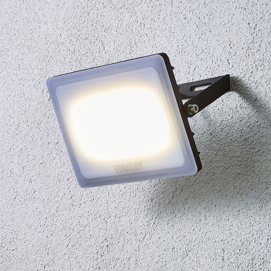 STANLEY SXLS38930E LED floodlight mounted on textured wall, side angle photography.