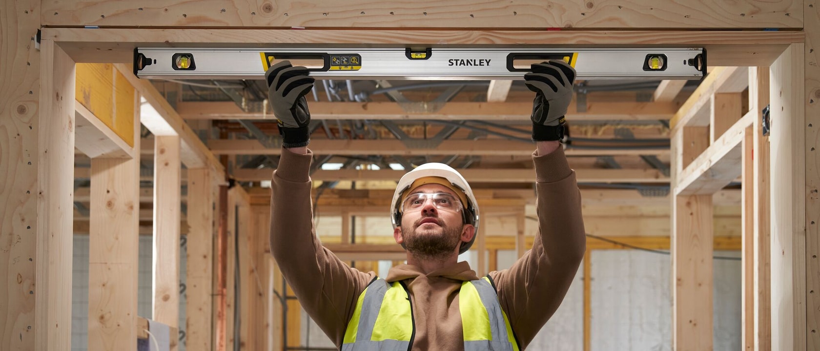Photo of a worker using a STANLEY FMHT43676-1 spirit level on a construction site, holding it up to a wooden frame.